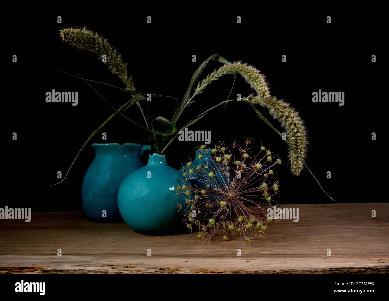 Stillleben mit drei blauen Vasen, Ähren und einer Blume einer Zwiebelbirne auf dunklem Hintergrund mit Licht von der rechten Seite Stockfoto