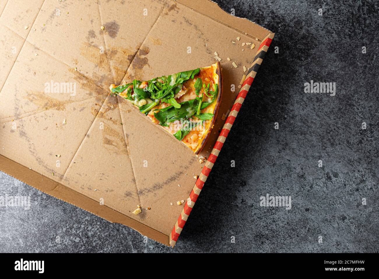 Oben Ansicht der letzten Scheibe Pizza in Pappkarton auf Steinküchentisch Stockfoto