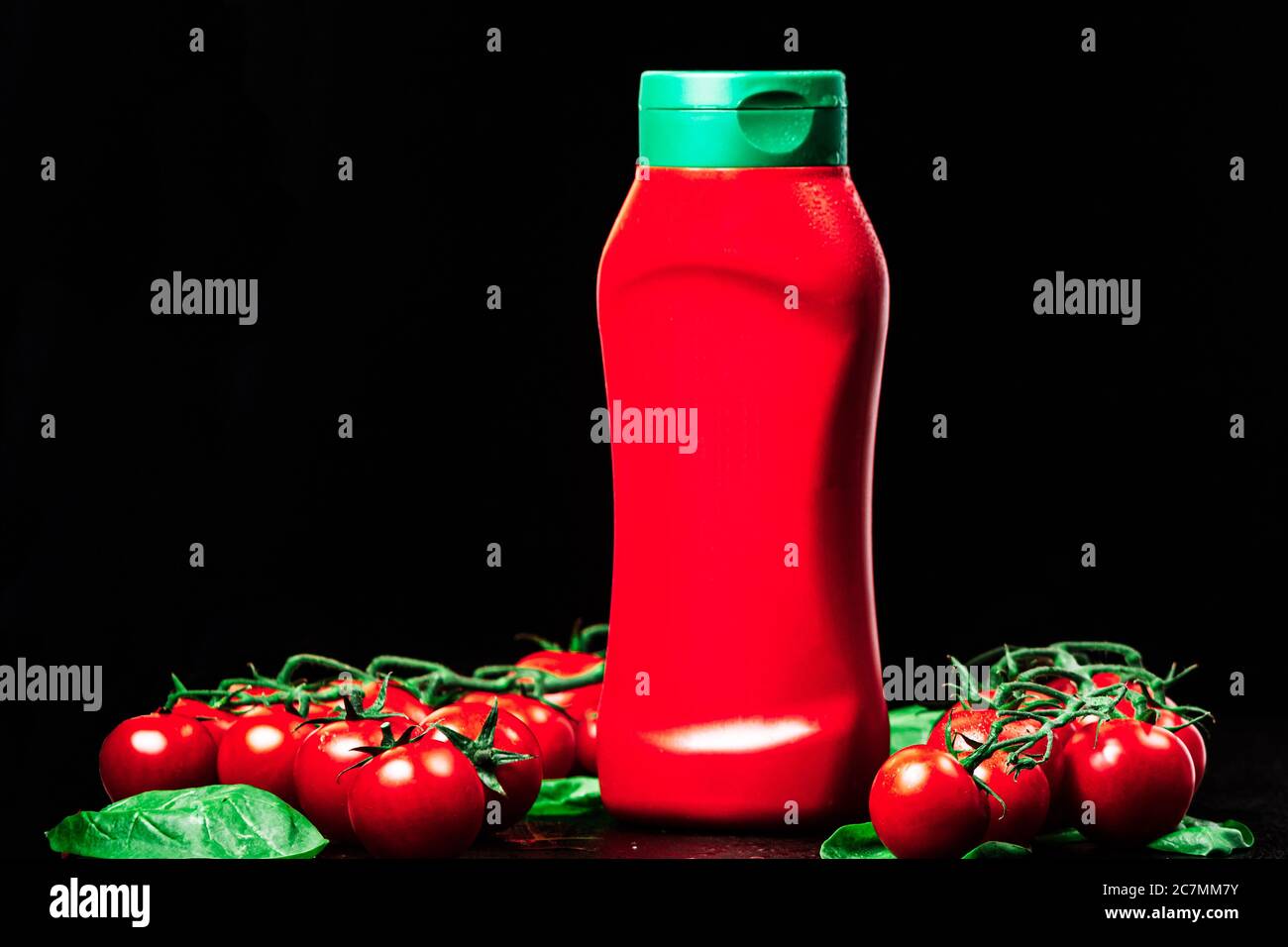 Flasche, Tube roter Ketchup mit grüner Kappe und zwei reife Zweige  Kirschtomaten mit Spinat auf schwarzem Hintergrund. Nahaufnahme,  horizontale Orienta Stockfotografie - Alamy