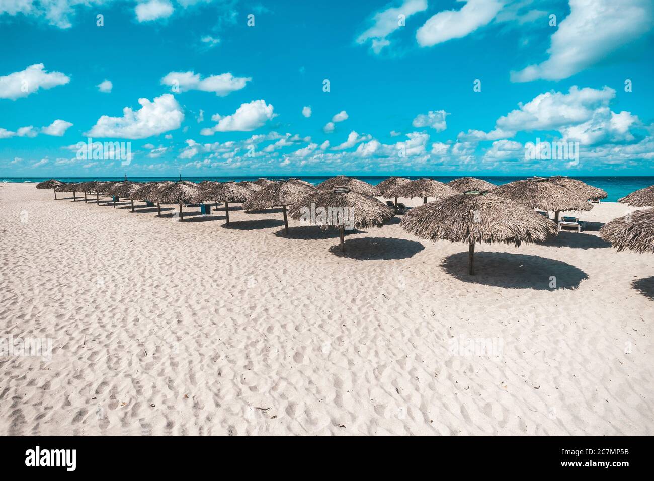 Viele reetgedeckte Sonnenschutze. Sonnenschirme stehen in einer Reihe auf Sand in einem Resort am Strand von Varadero in Kuba Stockfoto