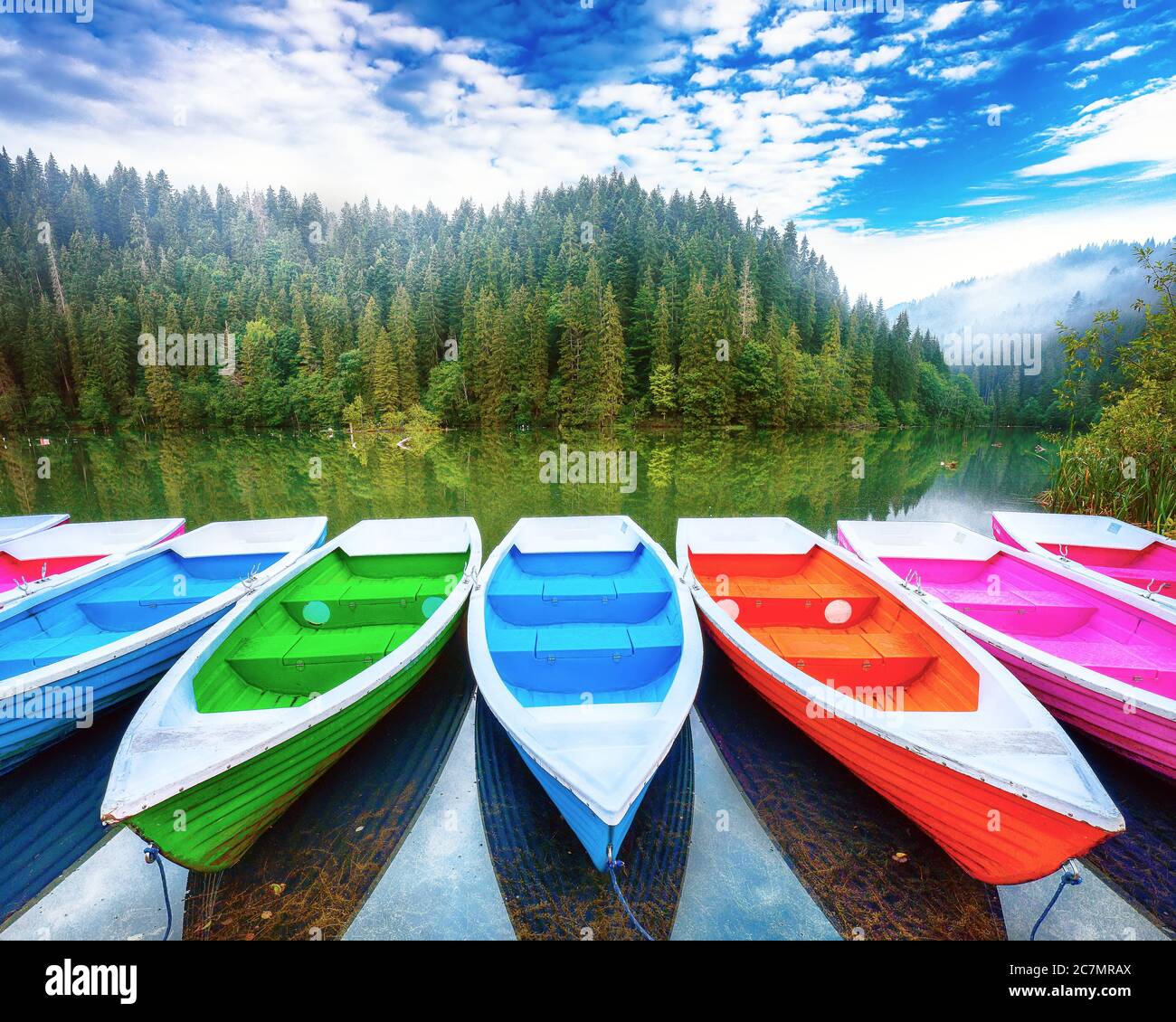 Boote auf dem majestätischen Bergsee Lacul Rosu oder Red Lake oder Killer Lake. Herrliche neblige Sommerszene des Lacul Rosu Sees in Harghita County, Eastern Carp Stockfoto