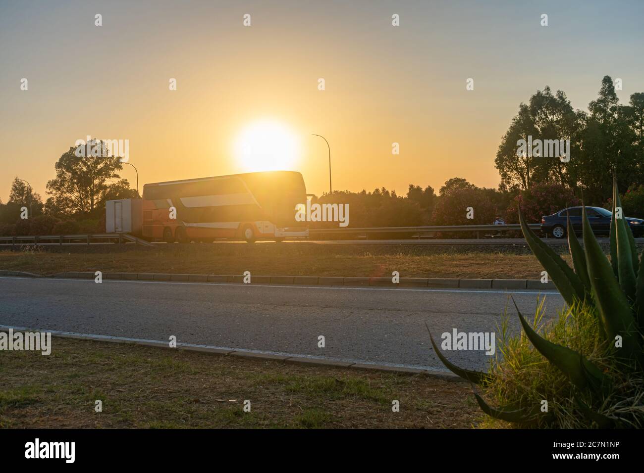 Bus mit Anhänger bei Sonnenuntergang auf der Autobahn Stockfoto