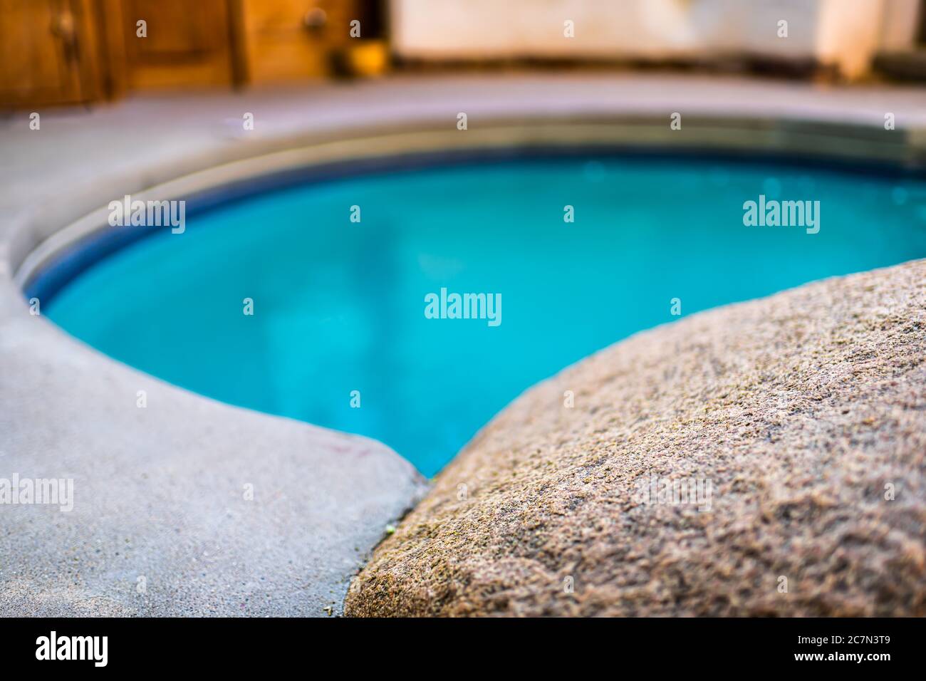 Japanisches Spa Stein Felsen Pool Rand Nahaufnahme mit türkis bunt blau Wasser heißen Quellen in Bokeh verschwommen Hintergrund in Japan Onsen Stockfoto