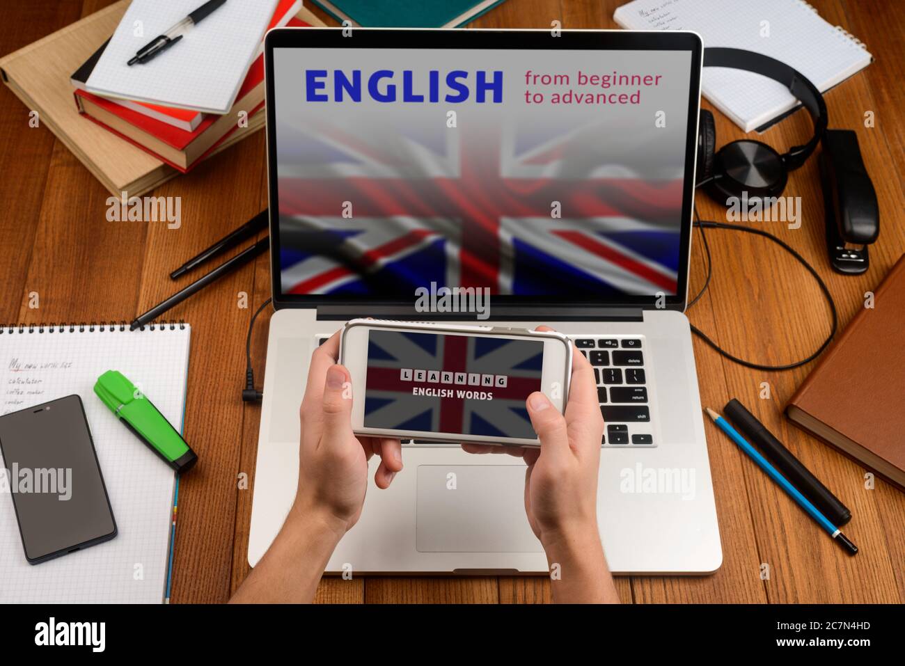 Englisch lernen online. Man öffnete Anwendungen auf seinem Telefon und Laptop Stockfoto