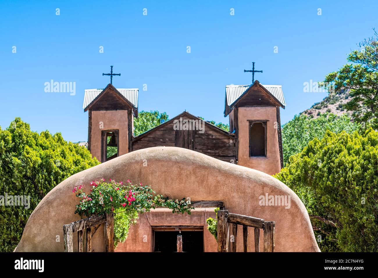 Berühmte historische Kirche El Santuario de Chimayo in den Vereinigten Staaten mit Eingangstor in der Nähe von Blumen im Sommer Stockfoto