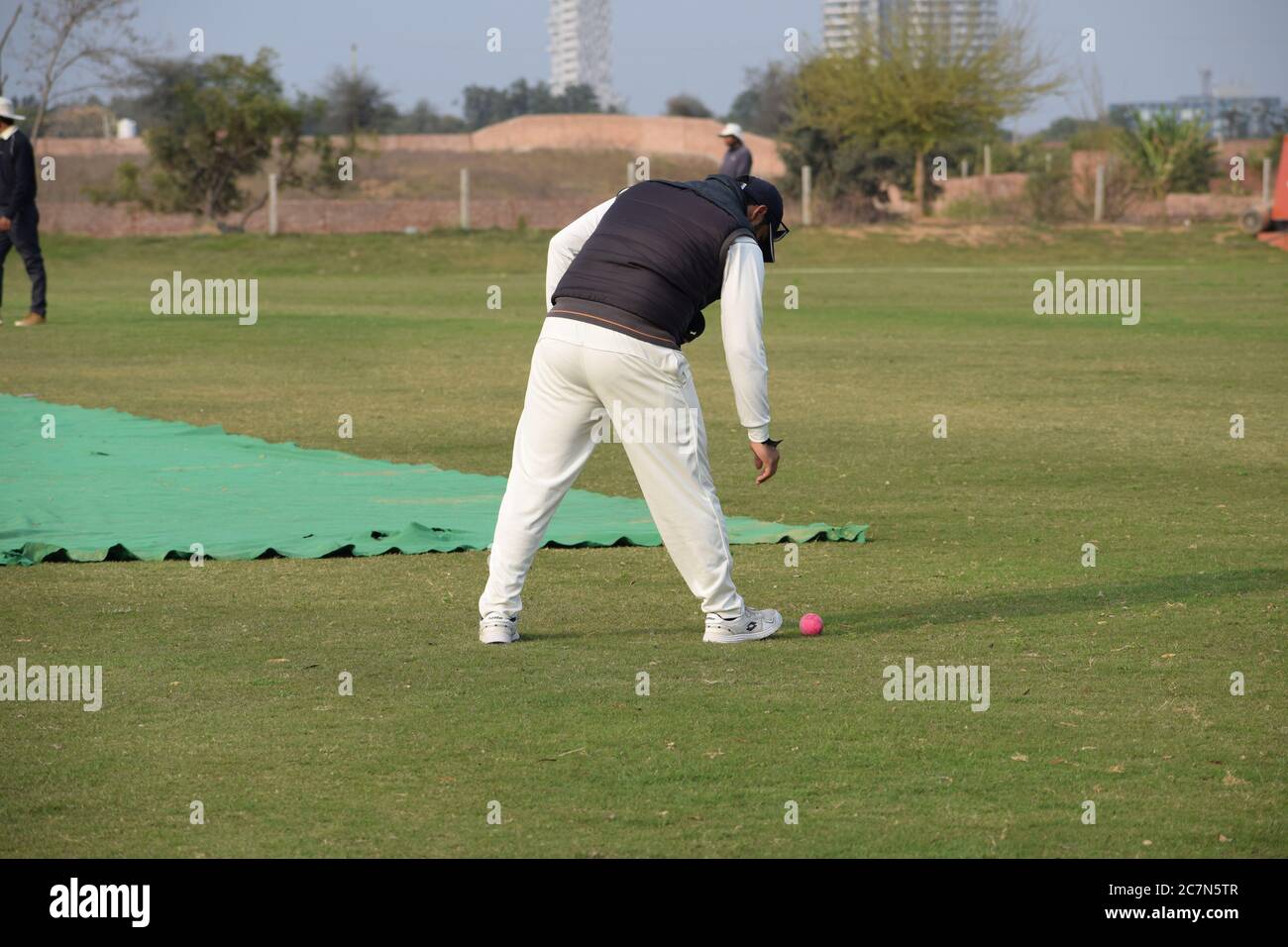 Cricketspieler spielen auf dem Feld während sonnigen Tag, Cricketspieler auf dem Feld in Aktion, Spieler spielen Cricket-Spiel auf dem Feld während des Tages ti Stockfoto