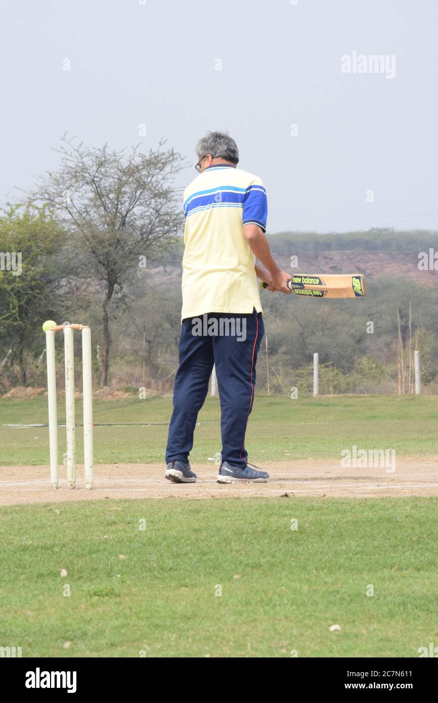 Cricketspieler spielen auf dem Feld während sonnigen Tag, Cricketspieler auf dem Feld in Aktion, Spieler spielen Cricket-Spiel auf dem Feld während des Tages ti Stockfoto