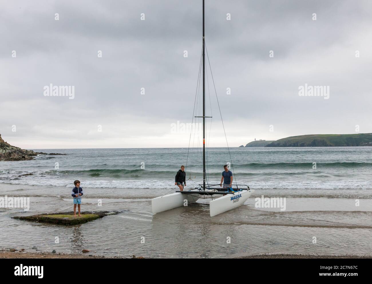 Red Strand, Cork, Irland. Juli 2020. Fionn beobachtet seine Eltern Mary Jane und Patrick McLaughlin, wie sie ihren neuen Nacra-Katamaran am Ufer von Red Strand, Co. Cork, Irland, aufstellten. - Credit ; David Creedon / Alamy Live News Stockfoto