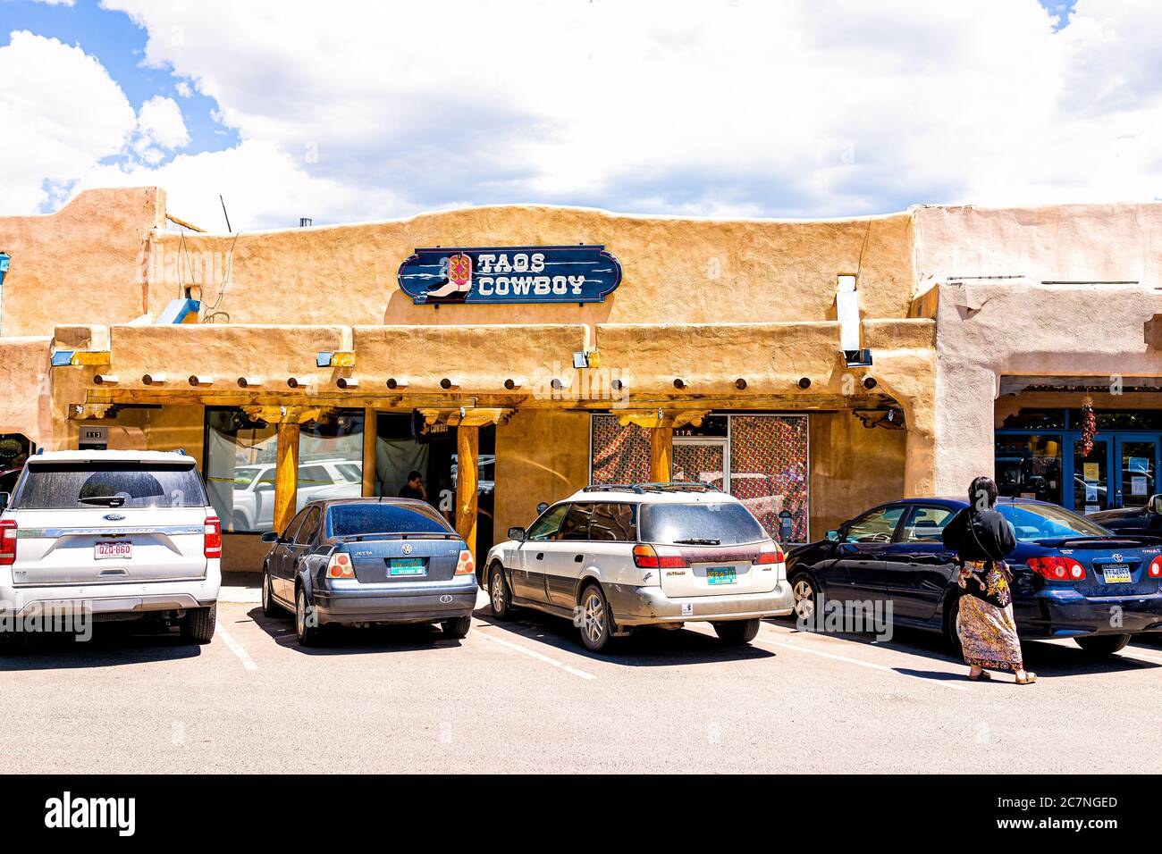 Taos, USA - 20. Juni 2019: Farbenfroher Plaza Platz in der Innenstadt in einem berühmten Stadtdorf mit Schild außen für Cowboy-Laden und Autos, die auf der Sonne geparkt sind Stockfoto