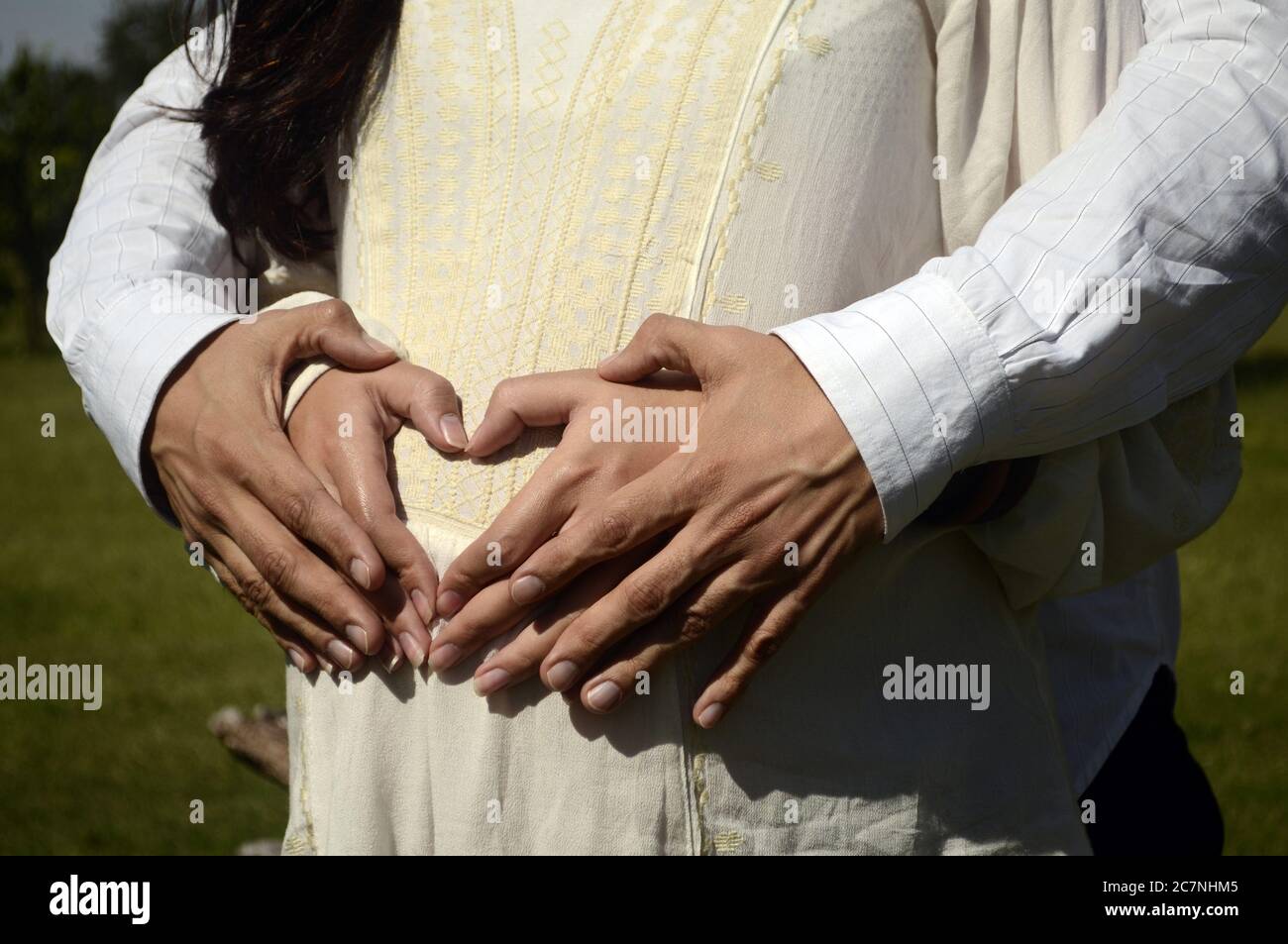 Paar macht Herzform mit den Händen auf schwangeren Bauch. Stockfoto