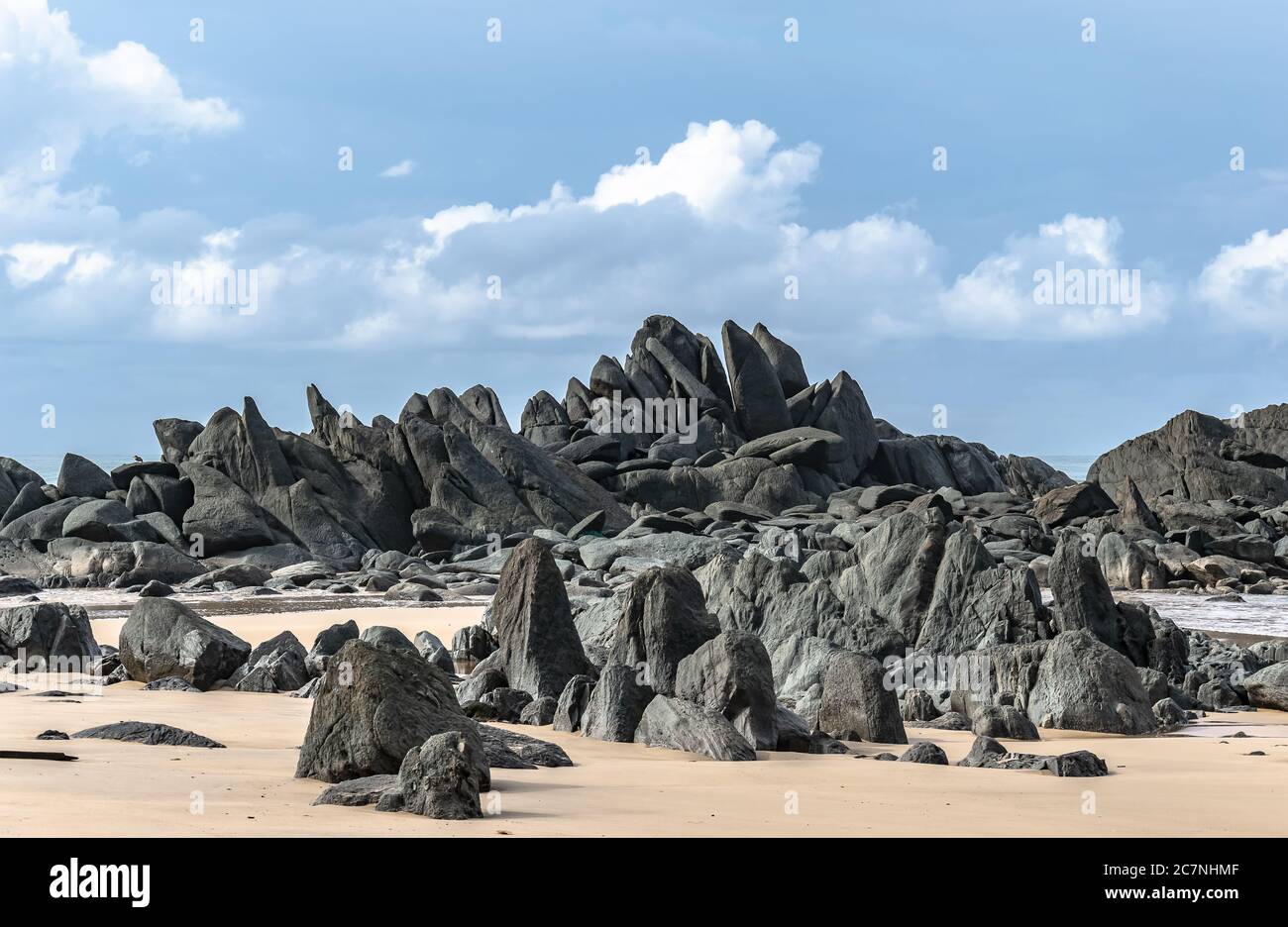 Schwarze dunkle Felsbrocken liegen an einem Strand nach der Küste in Axim Ghana Westafrika Stockfoto