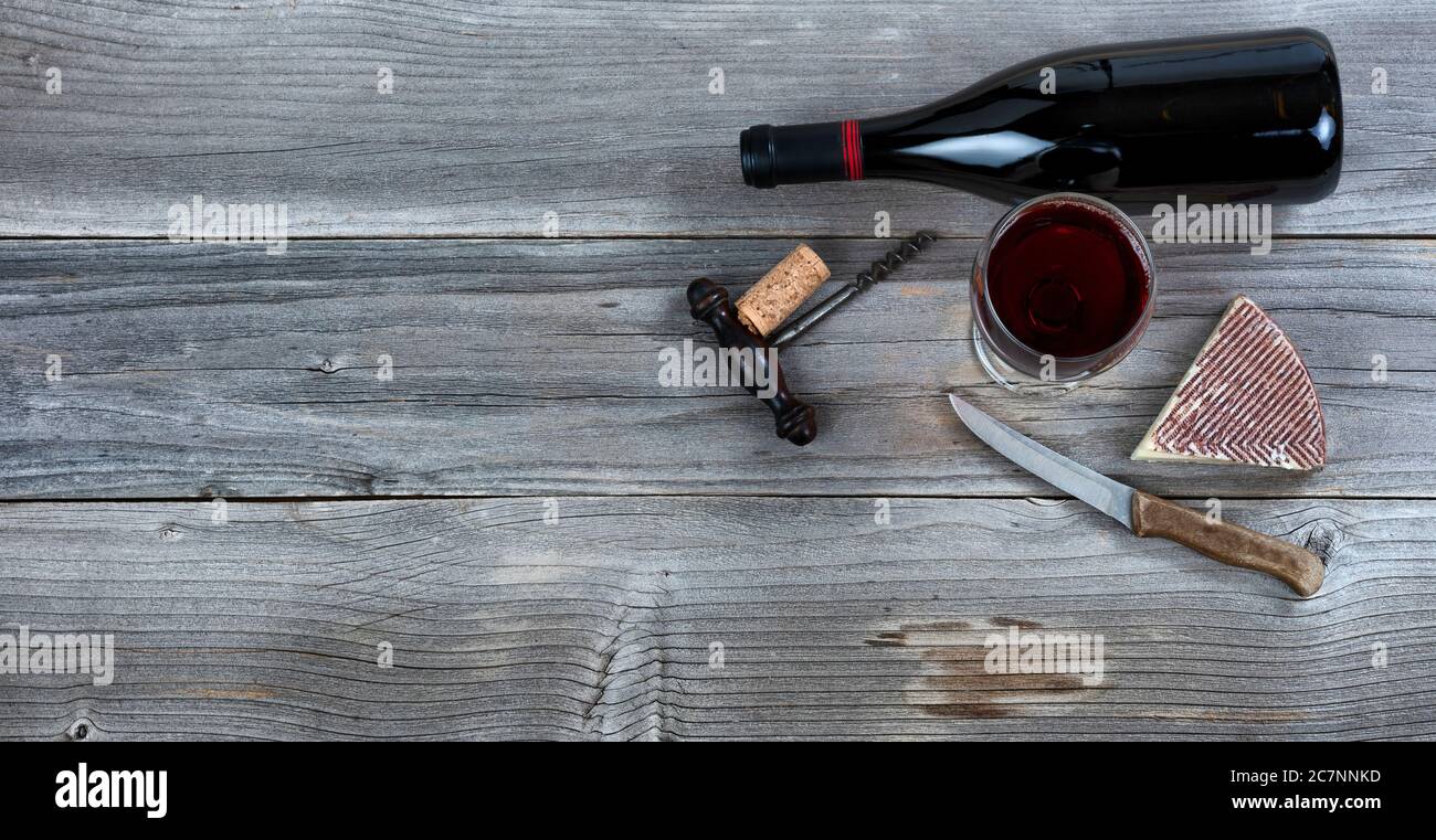 Frischer Käsekeil und Rotwein im Glas auf rustikalem Holz Stockfoto