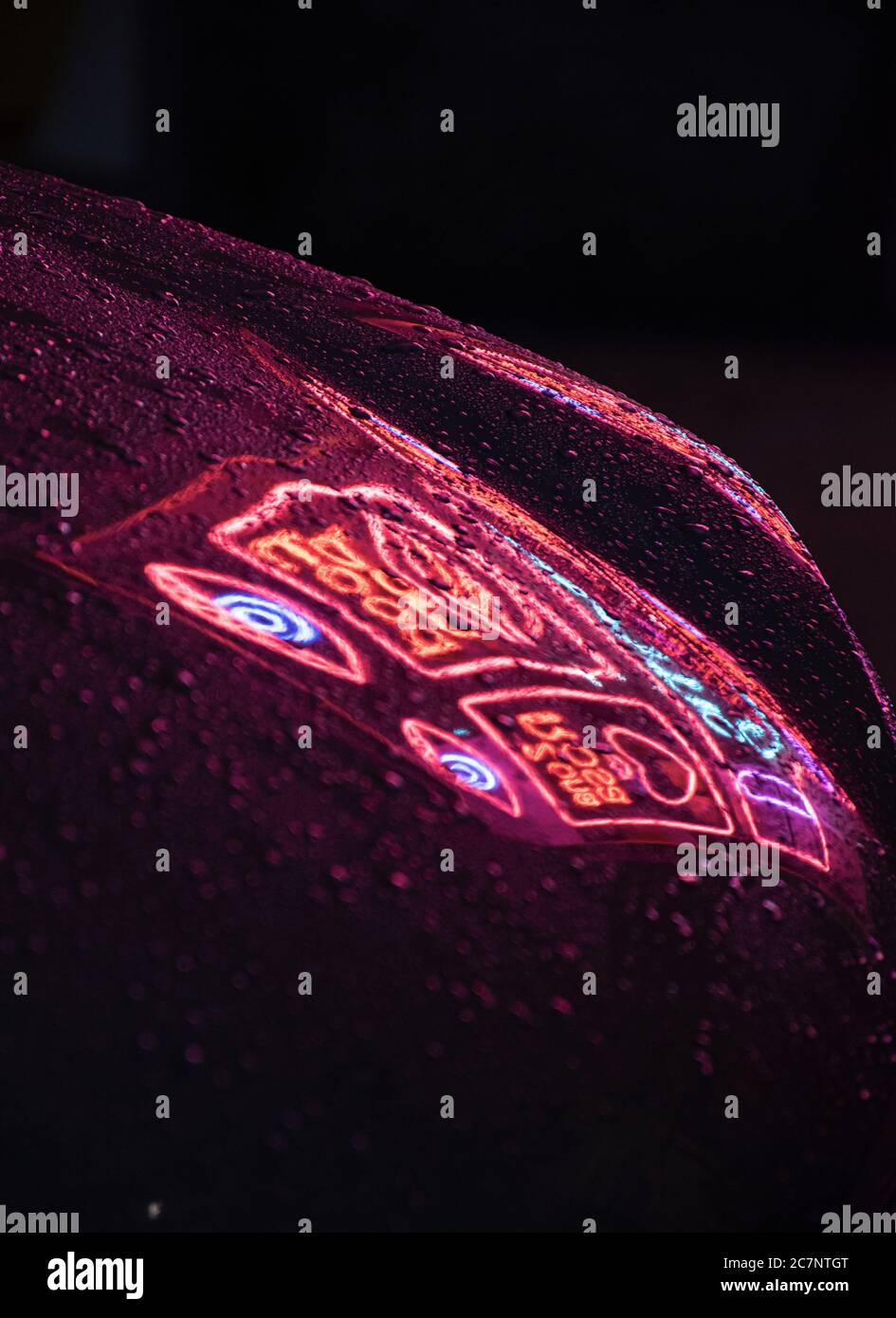 Neonspiegelung in einem Auto mit Regentropfen in der Nacht Stockfoto