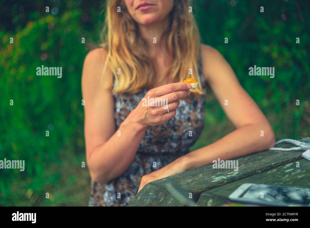 Eine junge Frau genießt ein Picknick an einem Tisch in der Natur Stockfoto