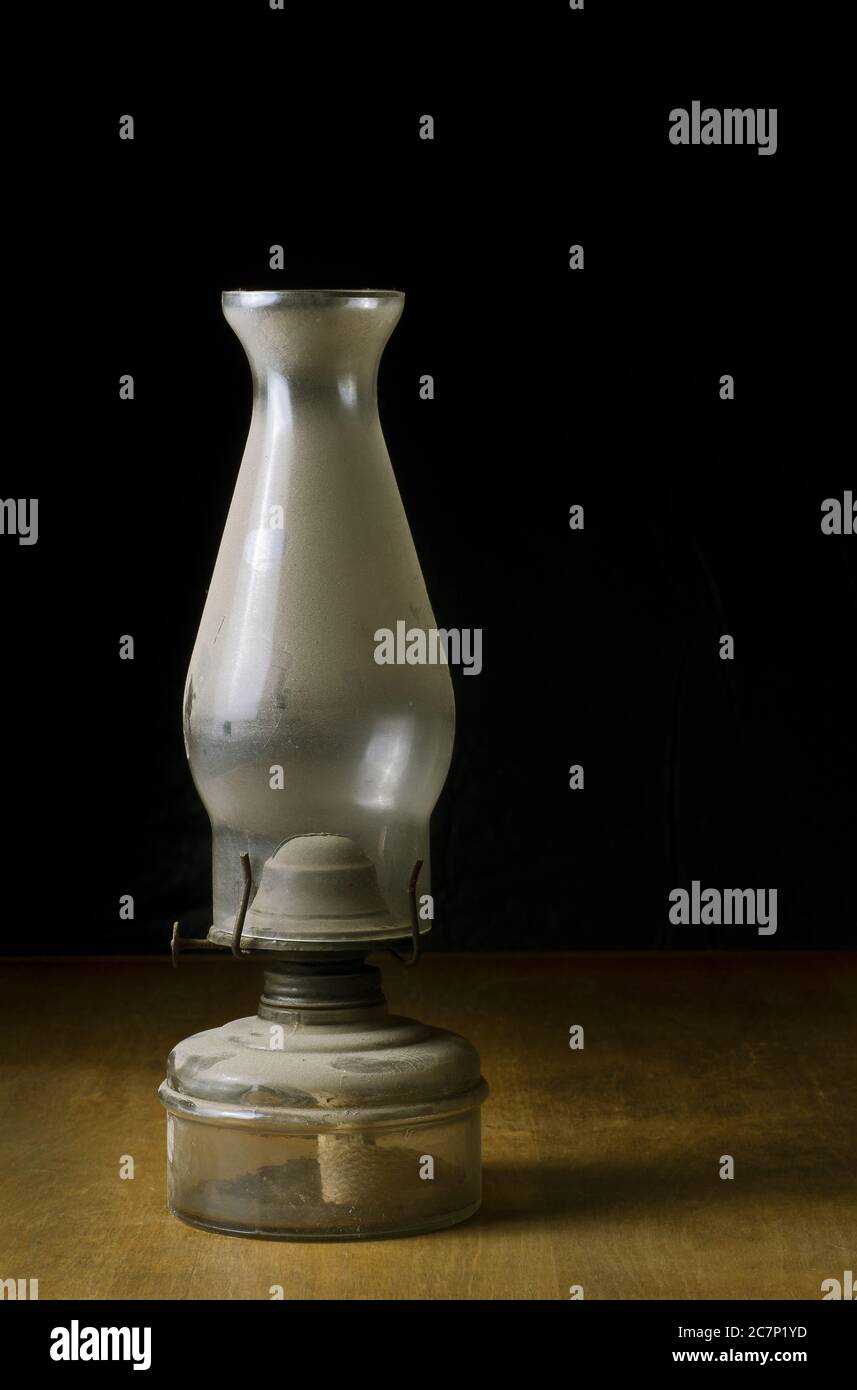 Eine vertikale Aufnahme einer alten staubigen Öllampe auf einem Holztisch Stockfoto