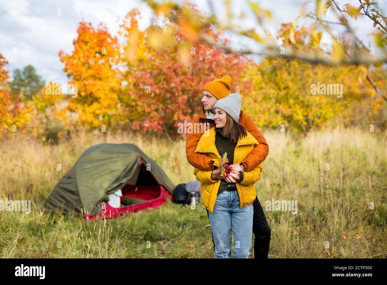 Reise, Liebe und Herbstkonzept - junges verliebtes Paar posiert in der Nähe von grünem Zelt im Herbstwald Stockfoto
