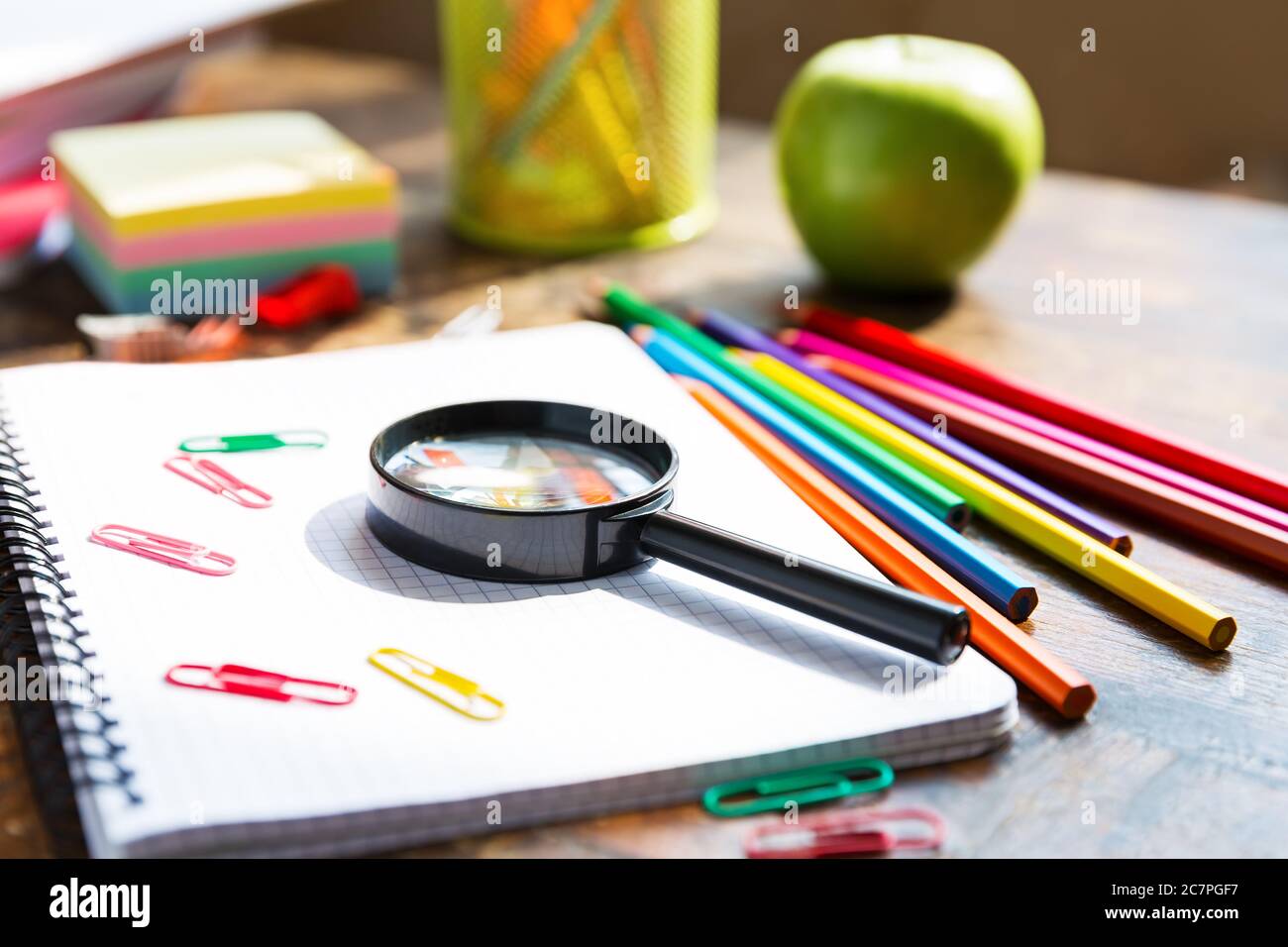 Zurück zur Schule: Notizbuch, Bleistifte, Lupe, grüner Apfel auf Holztisch Stockfoto