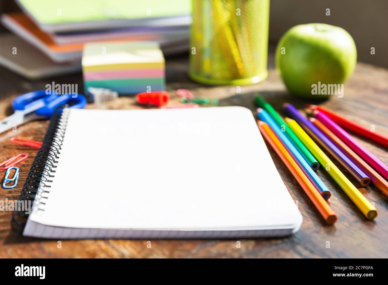 Zurück zur Schule: Notizbuch, Bleistifte, Lupe, grüner Apfel auf Holztisch Stockfoto