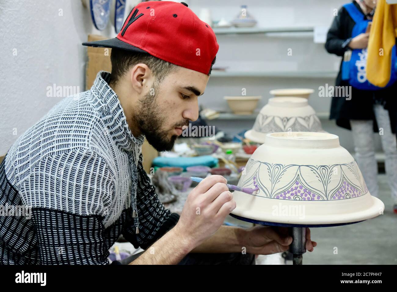 Junger Mann Zeichnung Keramik Tontöpfe. Blur Workshop und touristischen Hintergrund. Keramik ist traditionelle Industrie in Fez. Marokko Stockfoto