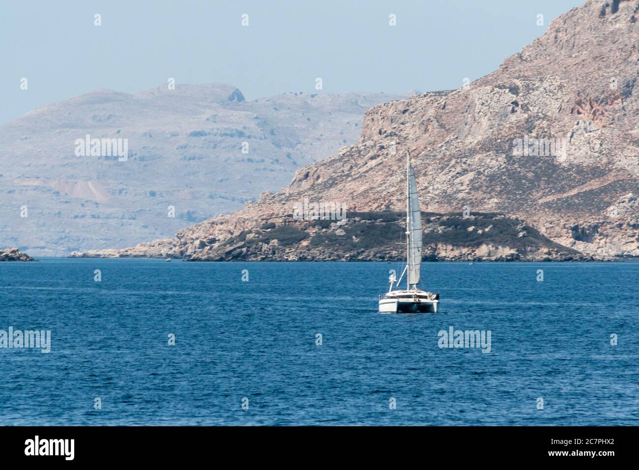 Katamaran segelt entlang der Küste von rodos in griechenland in einem ruhigen blauen Meer. Stockfoto