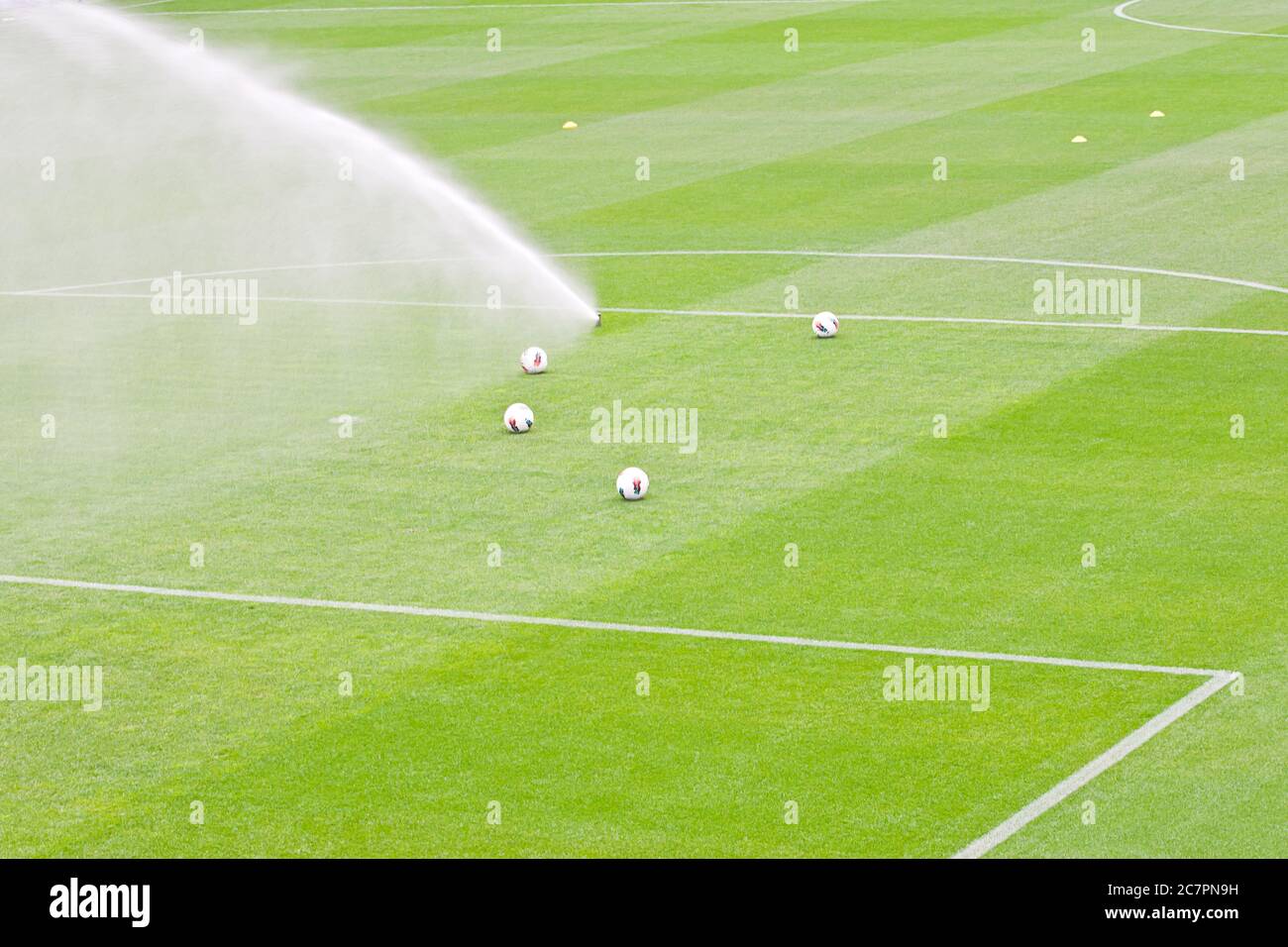 Bewässerungsrasen arbeiten auf dem frischen grünen Gras auf dem Fußballplatz Stockfoto