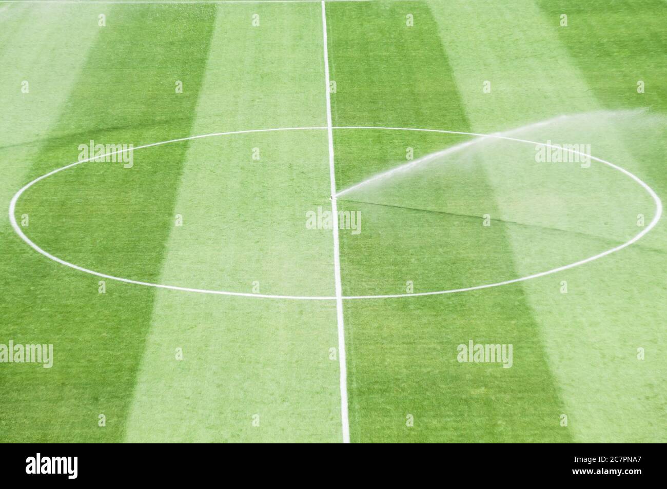 Bewässerungsrasen arbeiten auf dem frischen grünen Gras auf dem Fußballplatz Stockfoto