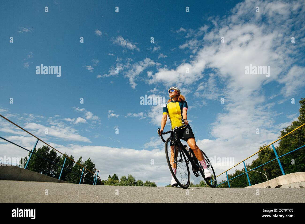 Low-Angle-Aufnahme einer Radfahrerin unter einem schönen Himmel mit hellen Wolken Stockfoto