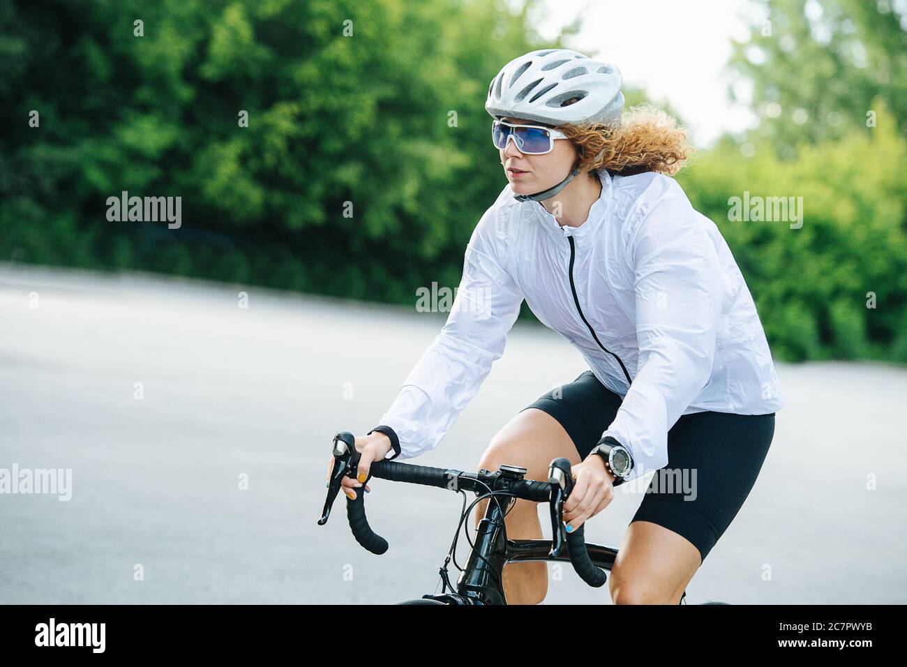 Junge sportliche Frau, die auf einem Profi-Fahrrad in einem weißen Helm Stockfoto