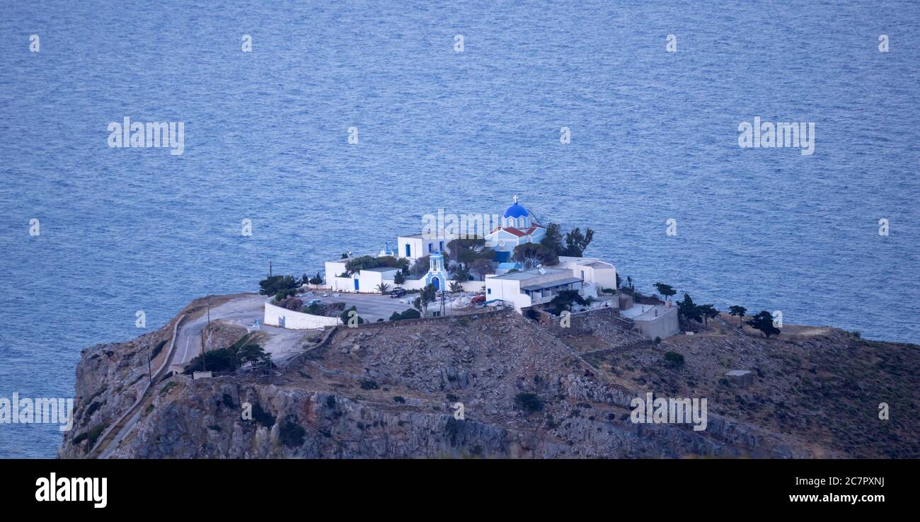 Griechisches Inselkloster, weiß und blau, traditionelle Architektur. Kirche und Nebengebäude auf der Spitze eines felsigen Hügels, Meereshintergrund. Gr Stockfoto