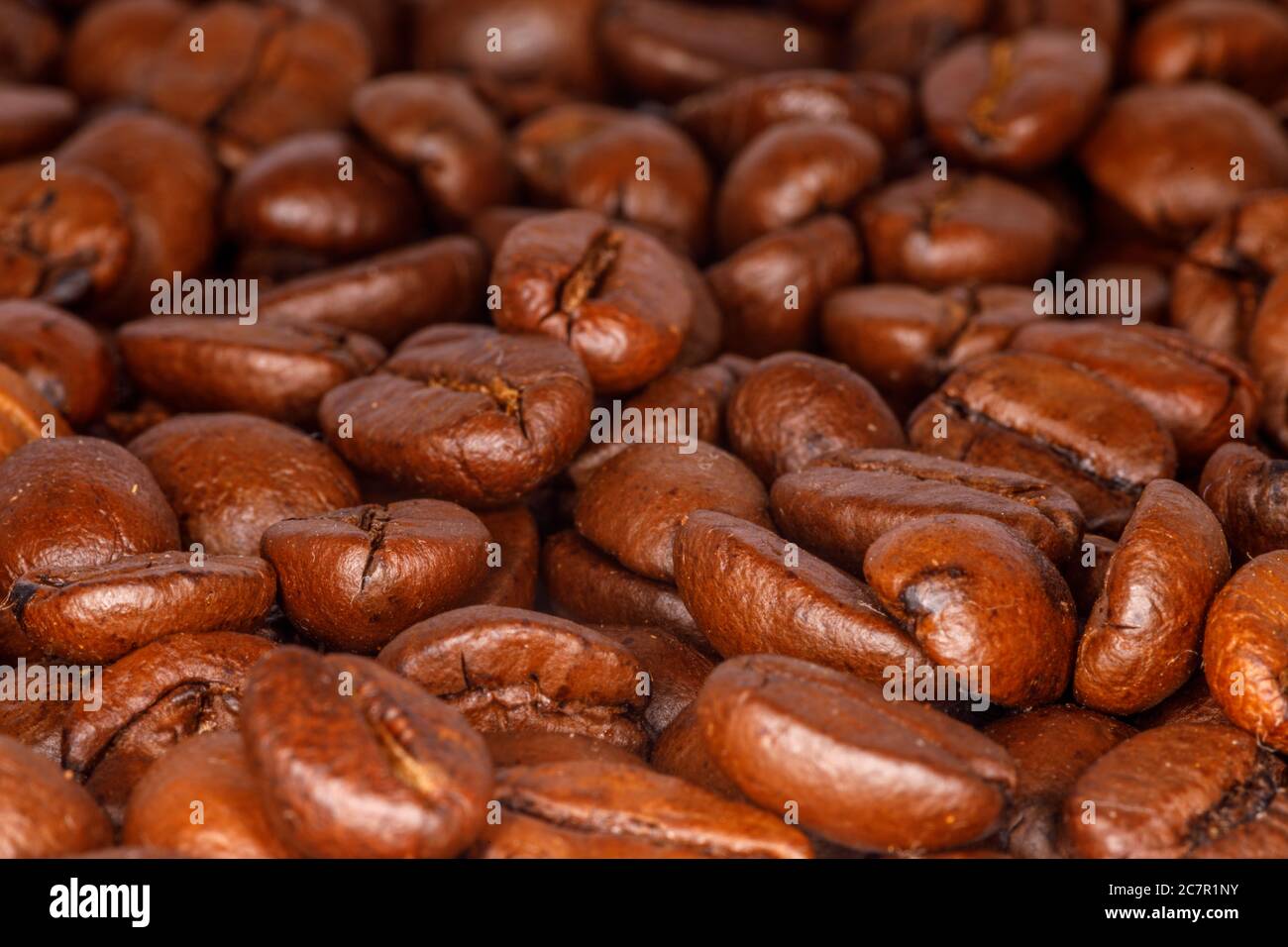 Nahaufnahme von gerösteten Kaffeebohnen, die auf einer Tischplatte verteilt sind Stockfoto