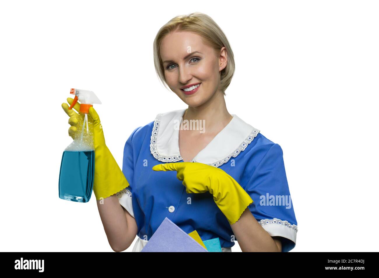 Haushälterin in Uniform, gelbe Gummihandschuhe Reiniger Spray auf weißem Hintergrund Stockfoto