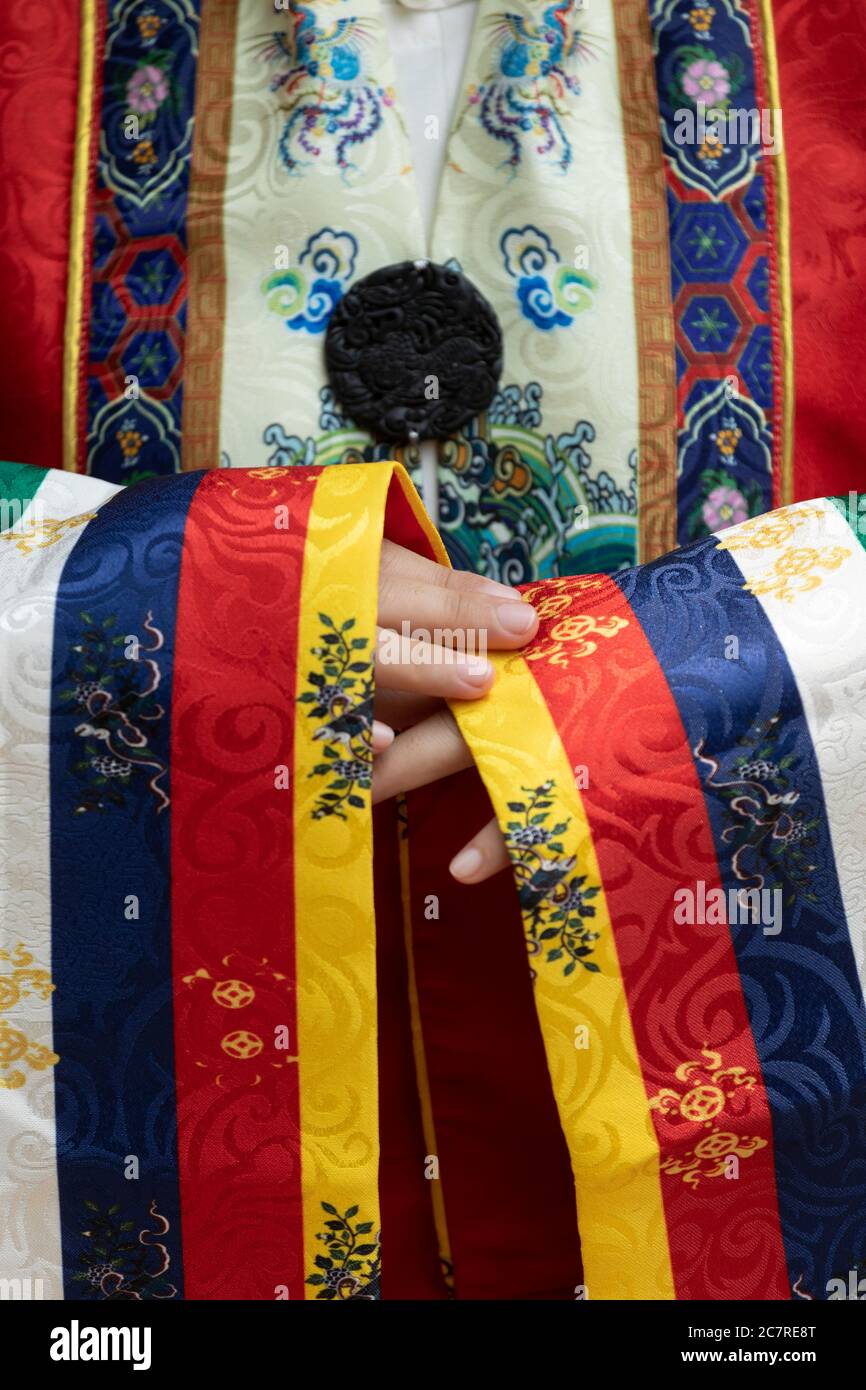 Nahaufnahme von Händen, Ärmeln und komplizierten Mustern vietnamesischer traditioneller königlicher Seidenroben mit den Farben Gelb, Blau, Rot und Weiß, die von Queen getragen werden Stockfoto