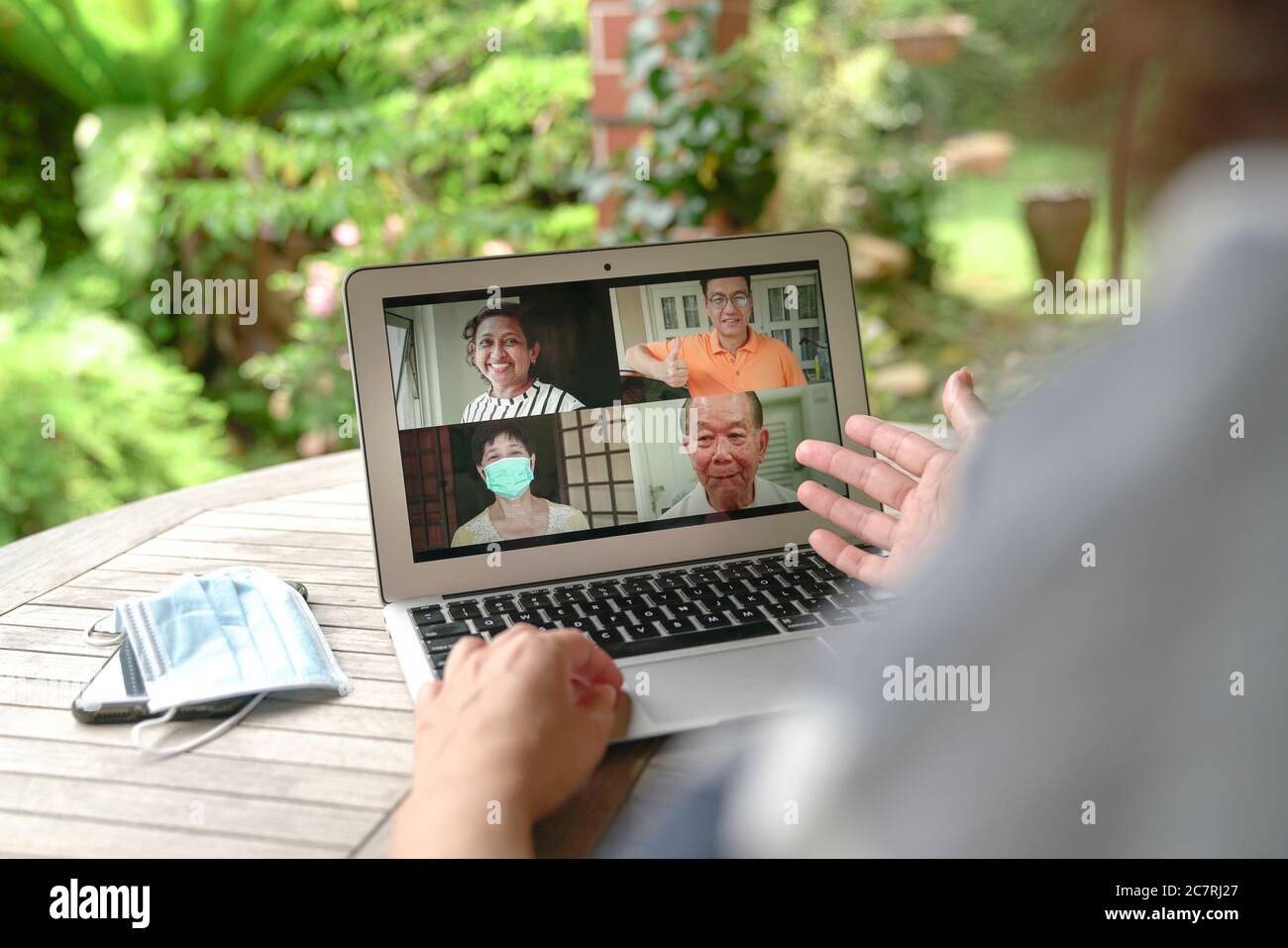 Frau mit Videoanruf und Chat mit Freunden über Computer Laptop zu Hause mit Blick auf den Garten Stockfoto