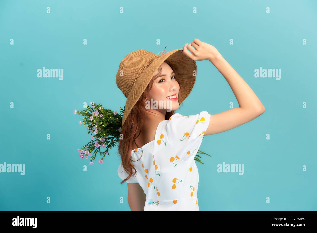 Mädchen in Hut und Blumenkleid Posen mit Blumenstrauß. Stockfoto