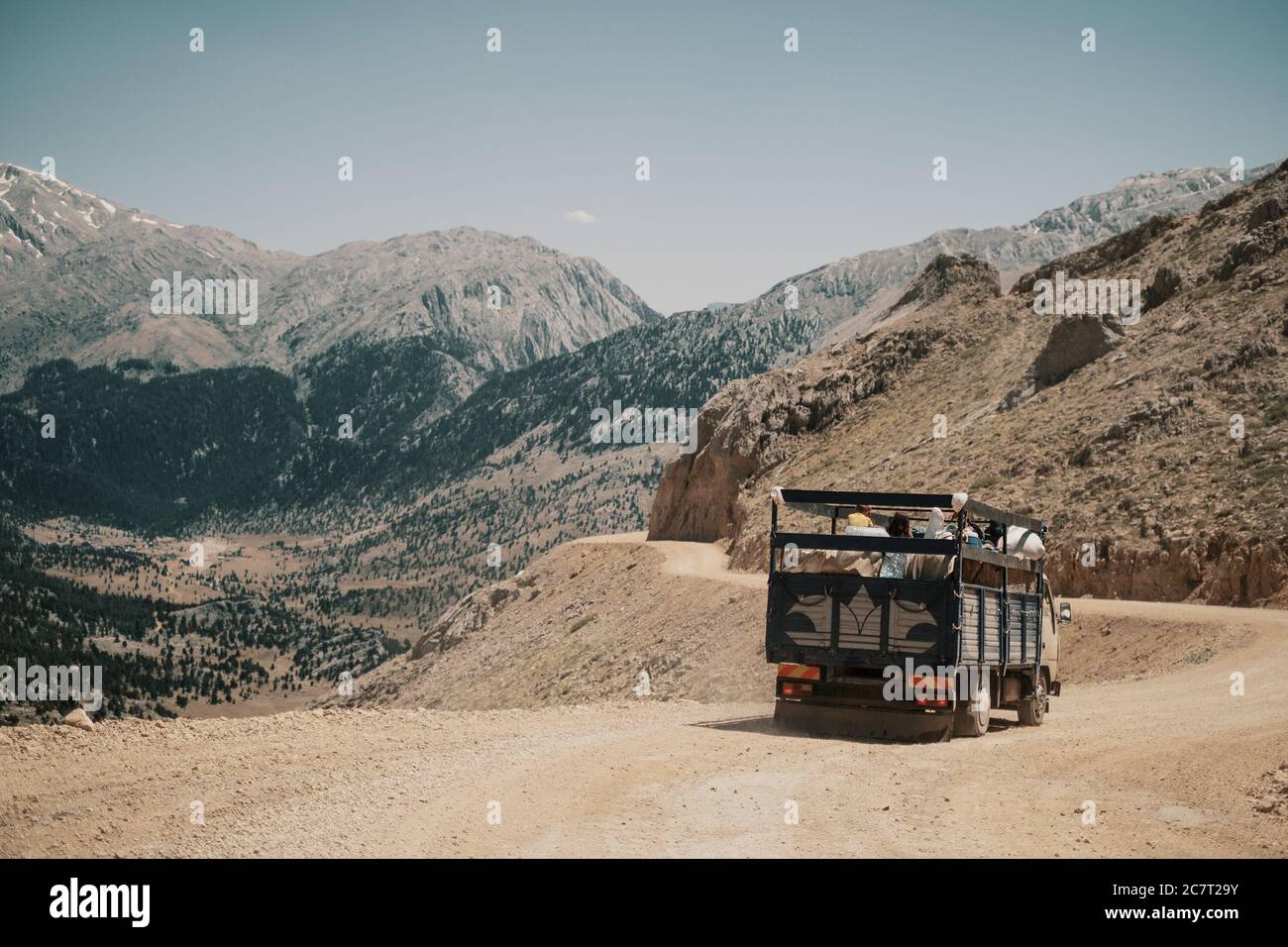 Classic Brown Big Rig Semi-Truck mit Step down Turn auf kurvenreichen Straße durch die Berge. Stockfoto
