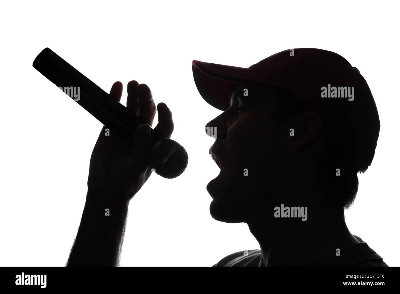 Junger Mann in Mütze singt in ein Mikrofon - Silhouette Stockfoto