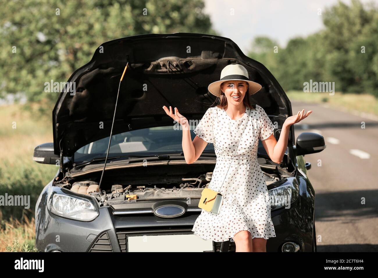 Junge Frau in der Nähe kaputtes Auto auf der Straße Stockfoto