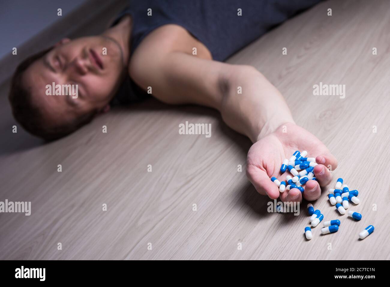 Überdosierung oder Selbstmord - junger stoned Mann mit Pillen auf dem Boden liegen Stockfoto