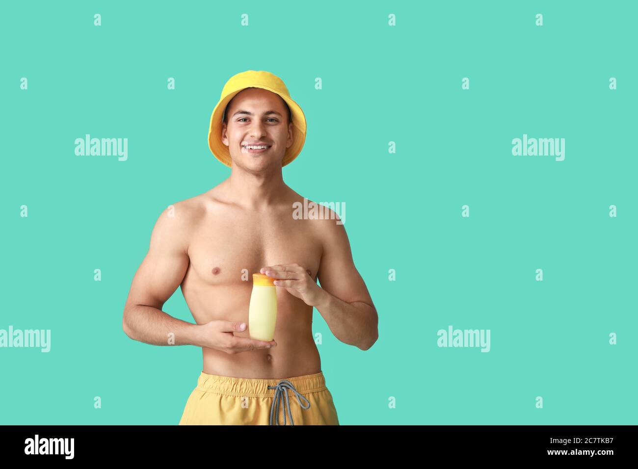 Fröhlicher junger Mann mit Sonnenschutzcreme auf farbigem Hintergrund Stockfoto