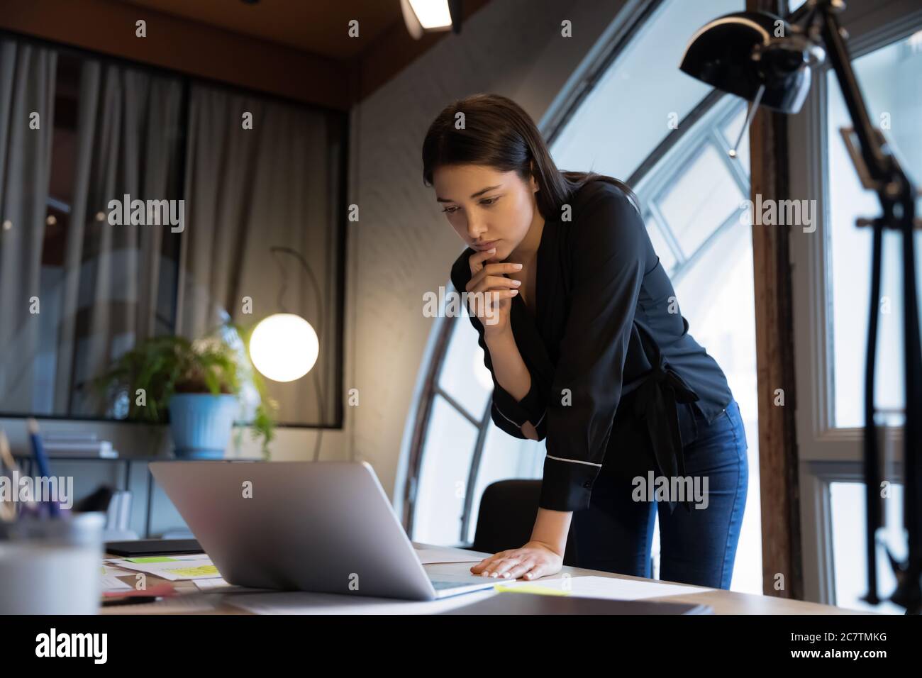 Nachdenkliche ethnische Geschäftsfrau betrachten Laptop Bildschirm Analyse Dokument Stockfoto