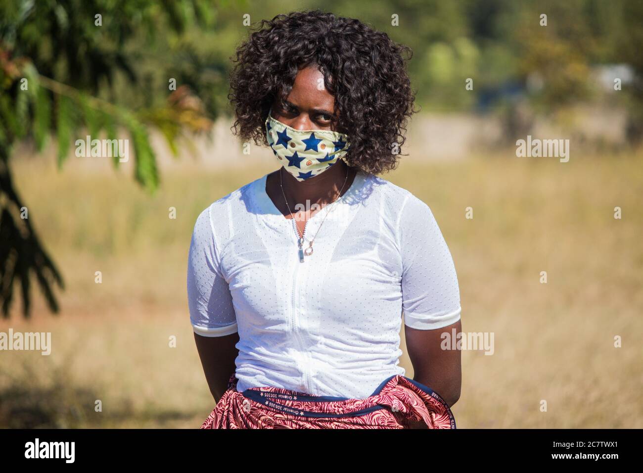 Frau trägt eine lokale handgemachte Gesichtsmaske aus traditionellem afrikanischen Stoff Sarong zum Schutz vor Corona-Virus Stockfoto Frau trägt eine lokale handgemachte Gesichtsmaske aus traditionellem afrikanischen Stoff Sarong zum Schutz vor Corona-Virus Stockfoto