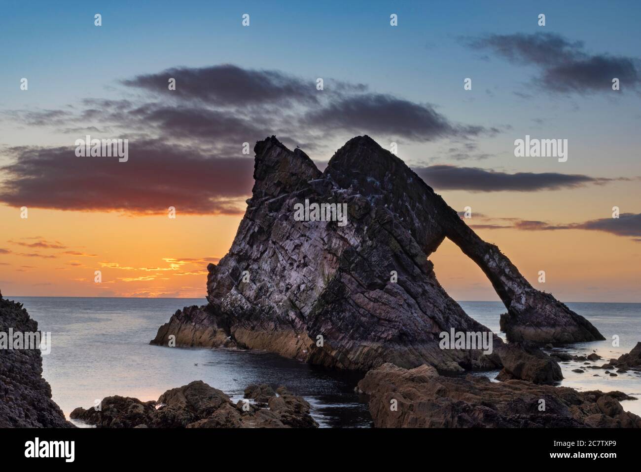 BOW FIDDLE ROCK PORTKNOCKIE MORAY COAST SCOTLAND SUMMER MORNING SONNENAUFGANG IM JULI GOLDENE WOLKEN VOR DER SONNE Stockfoto