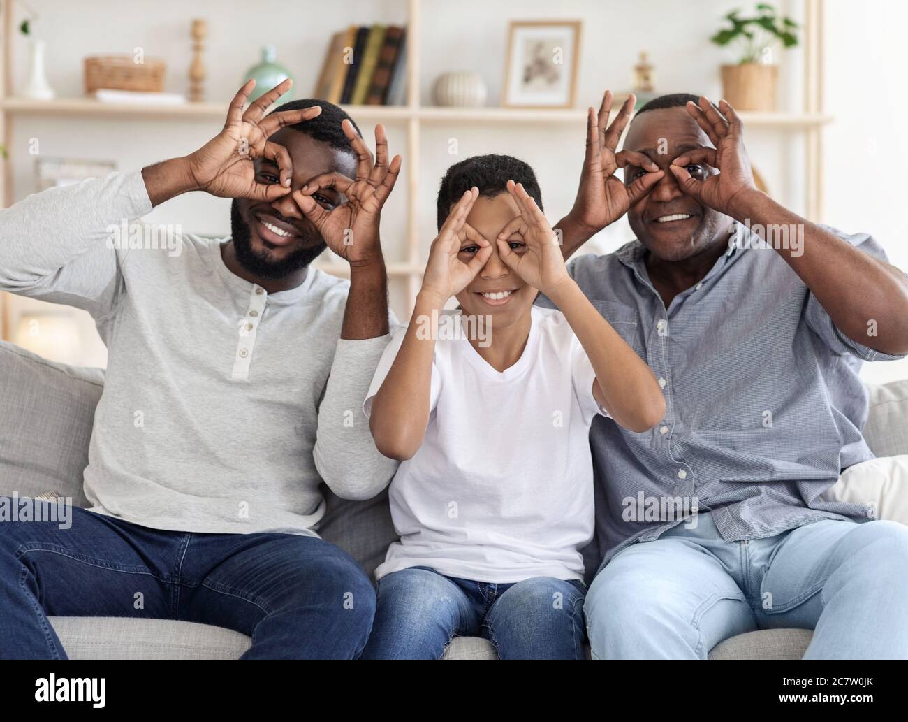 Zusammen Zu Hause Täuschen. Schwarze männliche Familie macht lustige Gläser mit Fingern Stockfoto