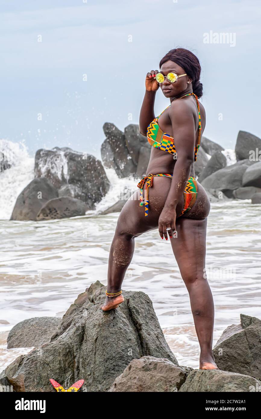 Ghana Frau steht auf Felsen mit Badeanzug am schönen Strand in Axim in Ghana, Westafrika. Stockfoto