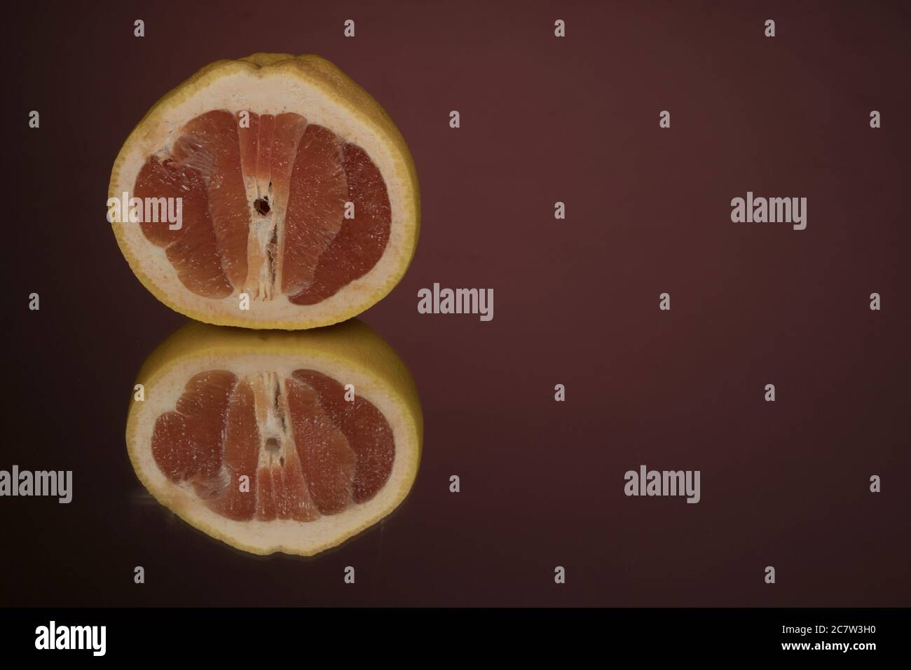 Halb transparente Grapefruitscheibe auf einem Hintergrund mit Spiegelung. Stockfoto