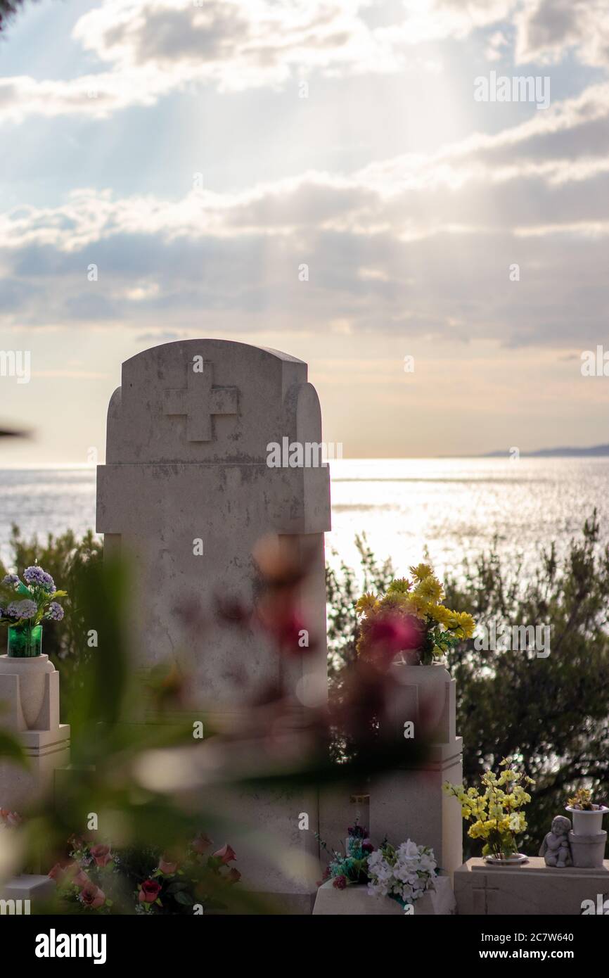 Alte traditionelle christliche Friedhof und Grabstein, in der Stadt Primosten an der adriaküste. Wolkiger Sommertag mit Sonnenstrahlen Stockfoto