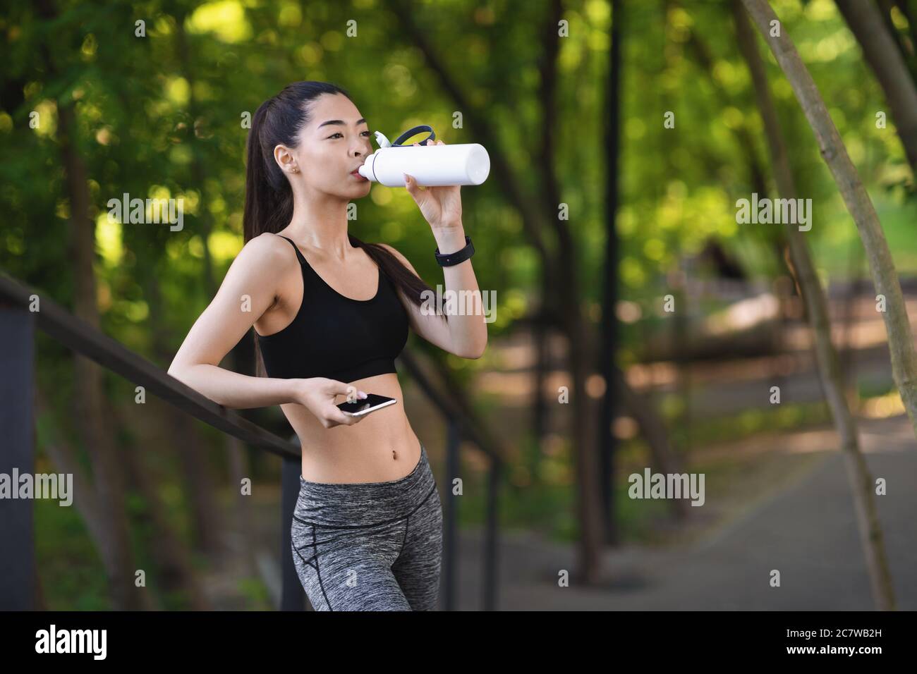 Glücklich junge asiatische Mädchen Trinkwasser nach dem Joggen im Park, die Ausübung im Freien Stockfoto