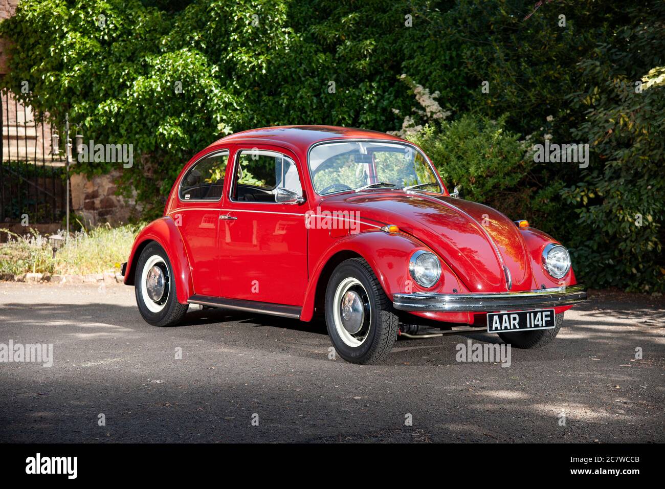 Volkswagen Beetle parkte an einem sonnigen Sommernachmittag auf dem Hof eines Hauses Stockfoto