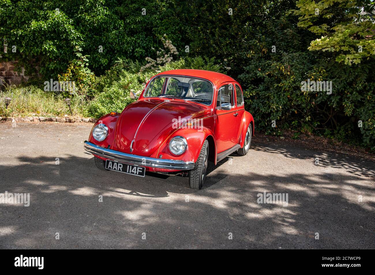 Volkswagen Beetle parkte an einem sonnigen Sommernachmittag auf dem Hof eines Hauses Stockfoto