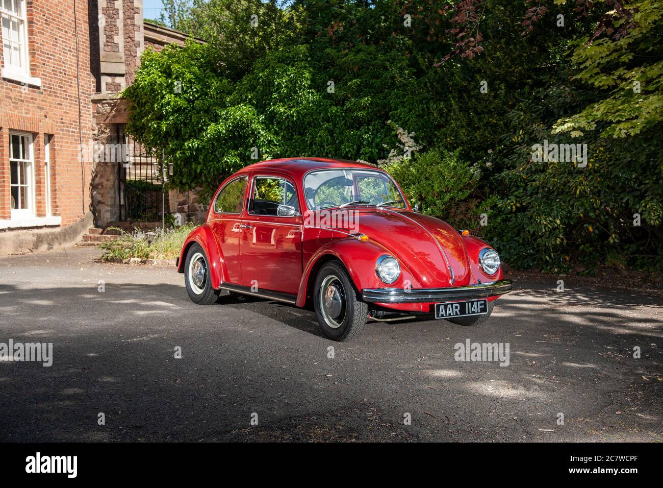 Volkswagen Beetle parkte an einem sonnigen Sommernachmittag auf dem Hof eines Hauses Stockfoto